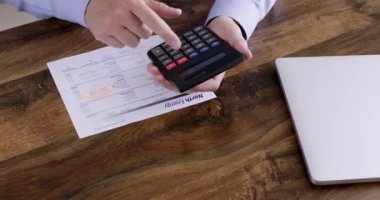 Serbest çalışan, hesap makinesinde matematik denklemleri çözmekte zorlanıyor ve tahta masaya bir alet fırlatıyor. İş adamının elektrik için yapılan toplu ödemelerle ilgili sorunları var