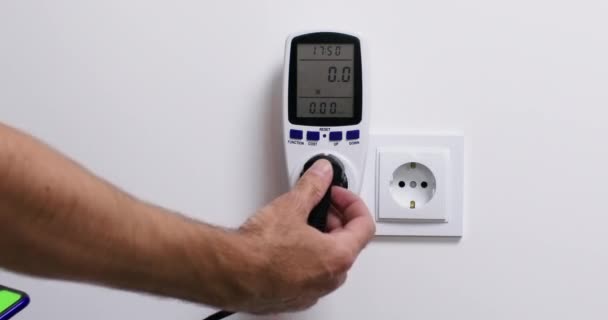 Человек Подключает Электрическое Устройство Розетке Домашним Ваттметром Измерения Энергопотребления Сравнивает — стоковое видео