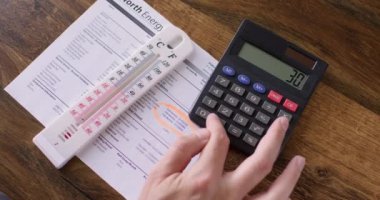 Freelancer checks electricity bill and tries to compare digits on paper and on trading market. Businessman counts on calculator and checks provided information