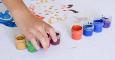 Children hands take gouache containers to paint amazing picture at home. Kids enjoy painting picture with paintbrush and spending time at home