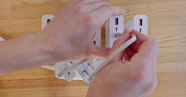 Man hands plug powerbanks to electrical extension cord on wooden floor close upper view. Charging power accumulating devices from network