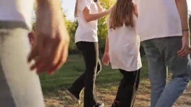 Bir grup genç ilginç hikayelere gülerek birlikte yürür. Parkta gün ışığıyla aydınlatılan kızlar iletişim kurar ve yürümekten zevk alırlar.