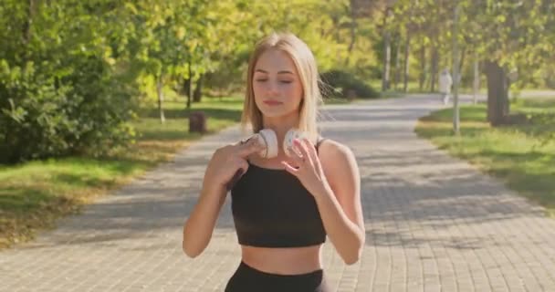 Perempuan Mengenakan Headphone Putih Untuk Mendengarkan Musik Energik Selama Berjalan — Stok Video