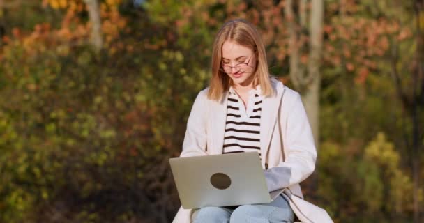Ung Kvinna Bär Glasögon Fungerar Laptop Höstparken Upplyst Solljus Blond — Stockvideo