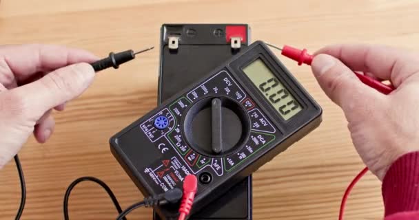 主用数字万用表检查木桌上蓄电池的压力 关闭上视镜 电气设备测试过程 — 图库视频影像