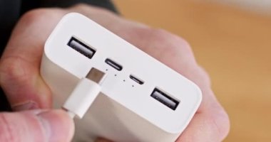 Adam arka plandaki bulanık çekimde mikro USB kablosunu Power Bank 'a takıyor. Cihaz şarjı için kabloyu aküye bağlıyorum. Elektrik gücü.