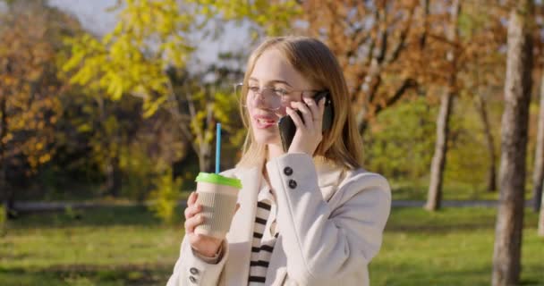 Ξανθιά Γυναίκα Απολαμβάνει Πίνοντας Καφέ Και Μιλώντας Φίλο Στο Smartphone — Αρχείο Βίντεο