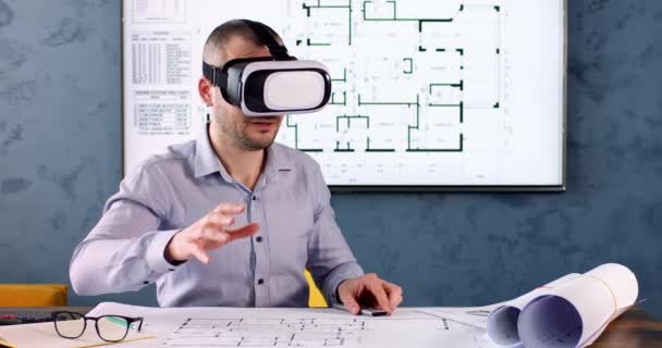 工程师使用远程控制器对虚拟现实耳机中新建的建筑进行了仿真 建筑师坐在写字台前 起草办公室草案 — 图库视频影像