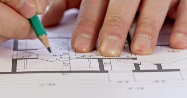経験豊富な建築家の手は 鉛鉛筆を使用してフロアプランを構築する上で測定値を書き込みます エンジニアは図面の測定値を計算します — ストック動画
