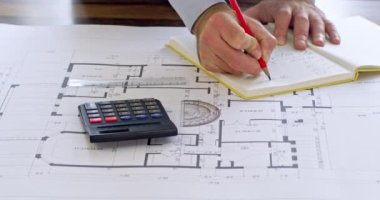 Mühendis hesap makinesi kullanarak çizim üzerinde hesaplamalar yapar. Mimar eller cetvel ve açıölçer ile uzunluğu ölçer. Adam not defterine not alıyor.