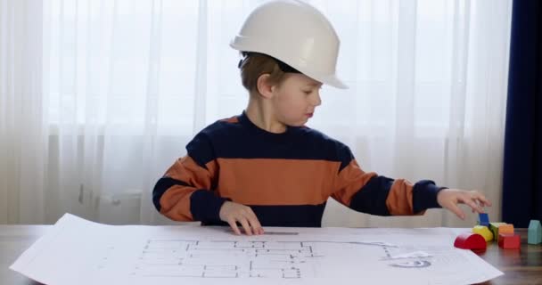 Przedszkolak Twardym Kapeluszu Odgrywa Rolę Budowniczego Wskazuje Palcem Rysunek Chłopiec — Wideo stockowe