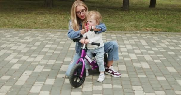 Young Mother Encourages Toddler Son Learn Ride Small Bike Green — Stock Video