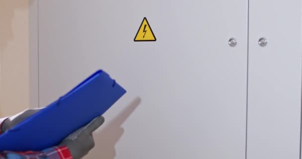 Electricista Apunta Pegatina Con Señal Advertencia Electricidad Sosteniendo Portapapeles Azul — Vídeo de stock