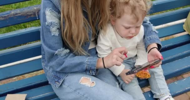 Anne Çocuğuna Şehir Parkında Akıllı Telefondan Oyunlar Gösteriyor Sarışın Çocuk — Stok video