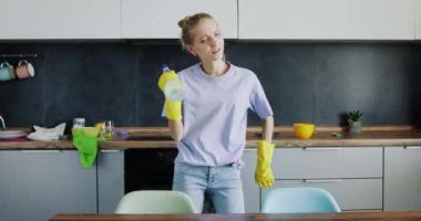 Genç dişiler ferah mutfakta dans etmekten hoşlanırlar. Mutfak işleri yapan mutlu ve keyifli bir kadın yorulmadan nefes almak için durur.