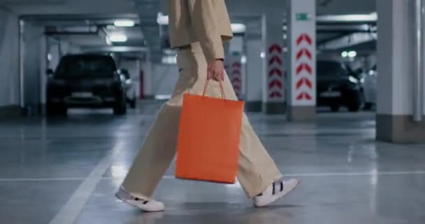 Blonde Geschäftsfrau Mit Einkaufstaschen Geht Durch Eine Tiefgarage Voller Autos — Stockvideo