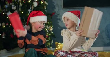 Anaokulu öğrencileri erkek ve kız Noel hediyelerini süslenmiş ağaçla tokuştururlar. Kardeşler evde birlikte yeni yılı kutlamayı severler.
