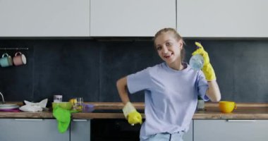 Dans eden genç ev hanımı geniş mutfakta şaka olsun diye şişeden su sıkar. Kadın sabah angaryasından zevk alıyor. Mutfak temizliği kavramı