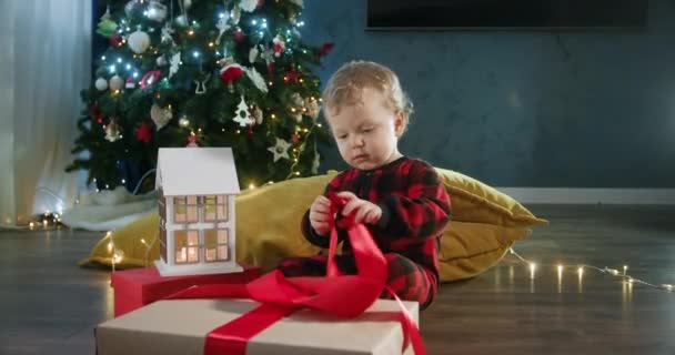 Menino Desempacotando Presentes Natal Contra Árvore Natal Decorada Sala Estar — Vídeo de Stock