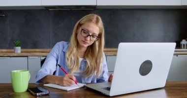 Genç bir kadın evde okuyor. Özenli bayan video dersleri izlemek ve yeni yetenekler kazanmak için dizüstü bilgisayar kullanır. Modern yaşam tarzı. Eğitim biçimi