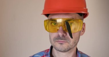 Kask takan işçiler, gözlüğü sıkışmış testere parçasıyla çıkarırlar. Çalışırken testere bıçağının bir kısmı güvenlik gözlüklerinin içine sıkıştı.