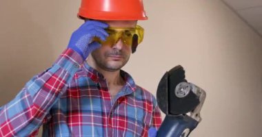 Kırık öğütücü diski olan bir işçi gri arka planda koruyucu gözlüğe sıkışmış. Kaza, koruma ekipmanlarının önemini gösteriyor