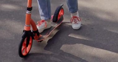 Sportif kız asfalt yolda modern scooter kullanıyor. Dişi ergen, güneşli bir günde hafta sonları aktif zaman harcamayı sever. Ekstrem sporlar