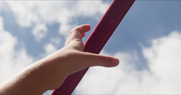夏天的时候 瘦小的孩子用他的手紧紧地握着水平的栏杆 与云彩相映成趣 在炎热的日子里 活泼的孩子伸臂锻炼身体 — 图库视频影像