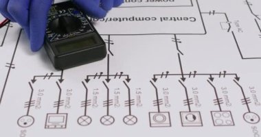 Mühendis devre ağını kontrol ediyor ve yukarıdan görüntü alırken tehlikeli bir bağlantı buluyor. Elektrikçi şemaya uyarı etiketi ekledi