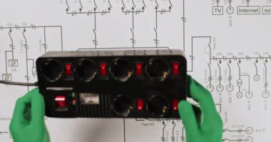Elektrikçi üst görünümü gösteren devre ağındaki aygıtları prize takar. Mühendis elektrik sistemi işini ve güvenliğini kontrol ediyor.