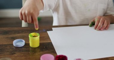 Küçük çocuk resim çizmek için parmağını boyaya daldırıyor. Sanata olan kız tutkusu deneyler ve yeni deneyler ile besleniyor.