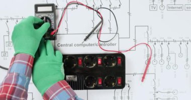 Teknisyen voltajı çoklu metre ile test eder ve şematik diyagrama uyarı işareti ekler. Elektrikçi elektrik şebekesini kontrol etti