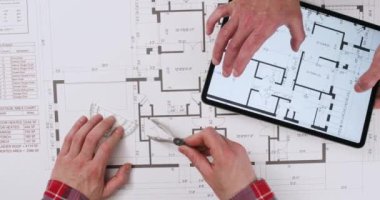 Tasarımcılar tablet ve manüel araçlarla zemin kat planını kontrol ederler. Mühendisler planların doğruluğunu kontrol ediyorlar. Daire planı.