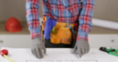 Elektrikçi şematik şemayı kontrol ediyor ve masa kapanışında uyarı işareti gösteriyor. Teknisyen şirket ofisindeki devre şebekesini inceliyor.