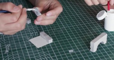 Küçük kız elleri kil tuğlaya yapıştırıcı sürüp masa kapanırken küçük bir ev yapıyor. Yaratıcı çocuk inşaat setinin seramik bloklarıyla çalışıyor.