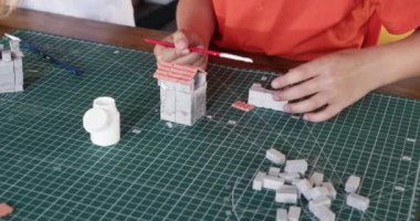 Küçük çocuk, yakın çekimde arkadaşıyla oyuncak kil tuğlaları kemer gibi yapıştırıyor. Yetenekli çocuklar sanat dersinde gerçekçi inşaat malzemeleriyle çalışırlar.