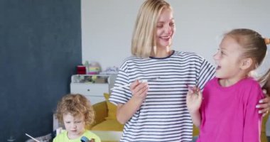 Anne kızının burnunun ucuna parlak kırmızı boya sürüyor. Sarışın anne ve kızı birlikte vakit geçiriyorlar. Kızının gözleri mutlulukla parıldıyor