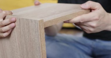 Anaokulu çocuğu ve insan komodin yapmak için tahta parçaları bir araya getirirler. Erkek ve çocuk elleri sıkıca birbirine uyan parçaları dikkatlice eşleştirir.