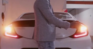 Sürücü eldivenleri ayarlar ve lastik tekerleklerle bagajı açar. Adam yeraltı koridorundaki acil durum alarmında lastik değiştirmek için arabadan lastikleri çıkarıyor.