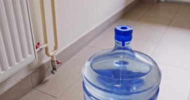 Adam serinletici kabı yerden kaldırmak için su şişesinin üstüne koyuyor. İnsan, uygun ulaşım ve sıvı teslimatı için yapı oluşturur