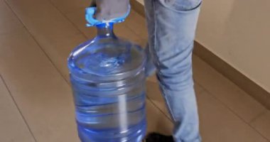 Teslimatçı su şişesini taşıyıp koridora çıkıyor. Kurye, sipariş edilen sıvı konteynırı teslim etmek için sakince apartmanın kapısına doğru ilerliyor.