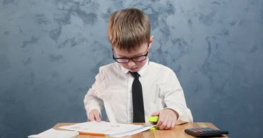 Sonuca odaklanmış gözlüklü öğrenci, sonuçtan memnun. Kravat takmış kendini adamış okul çocuğu masasında zımbayla gururla gülümsüyor.