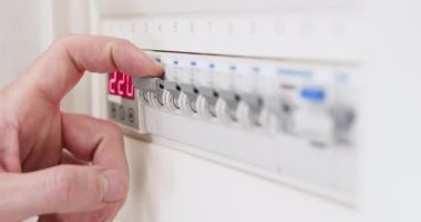 Adam devre kesici paneldeki elektrik düğmelerini kontrol ediyor. Elektrik işçisi inşaattaki işlevselliği test etmek için elektriği açıp kapıyor