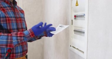 Elektrikçi adam tamirat sonuçlarını ev sahibine açıklıyor. İşçi, enerji sağlayıcıdan adama sunulan hizmetlerin faturasını verir