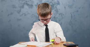 Sonuca odaklanmış gözlüklü öğrenci, sonuçtan memnun. Kravat takmış kendini adamış okul çocuğu masasında zımbayla gururla gülümsüyor.