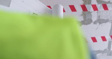 Uzman, el ele tutuşarak geniş bir kat planı hazırlıyor. İnşaatçı salonda duruyor ve dairenin yenilenmesine ilişkin gelecekteki adımları düşünüyor.