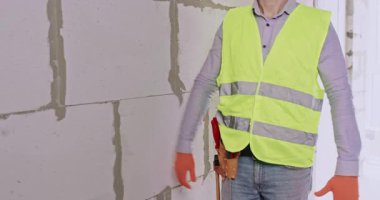 Mühendis, apartmandaki beton blokların yanında başparmak kaldırıyor. İnşaat uzmanı olumlu bir jest gösterdi ve tamiratın başarısını gösterdi