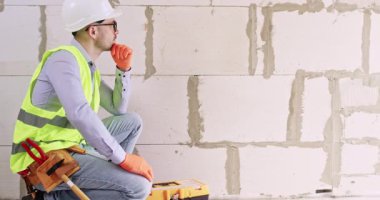 Mühendis yenileme işlemi sırasında yapılan hatalar için kömür bloğu duvarını inceliyor. Miğferli erkek uzman, dairede daha yumuşak bir yüzey oluşturmaya hazırlanıyor.