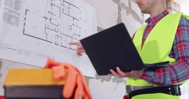 Uzman çalışmalar katın planı bilgisayarın ellerindeyken duvara sabitlendi. Profesyonel, özel hesaplamalar yapmak ve bina düzenini analiz etmek için modern dizüstü bilgisayar kullanır