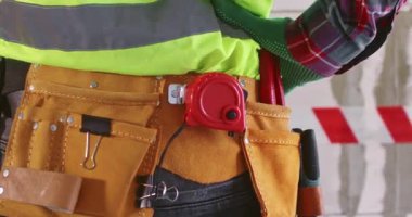 Adam duvarın karşısında duran şeritlerin performansını kontrol ediyor. Alet kemeri olan inşaatçı yenileme işleminden önce oda tahmini alanına başlamaya hazırlanıyor